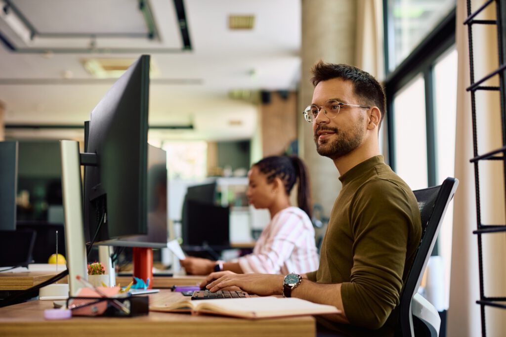 Young programmer working on desktop PC in the office of a software company.